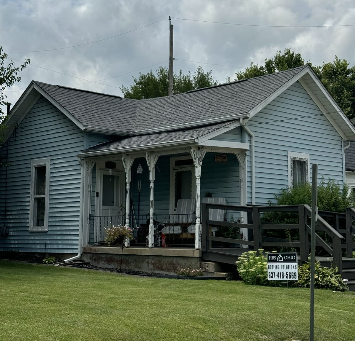 Blue-gray period home with a full-width covered porch and a completed roof