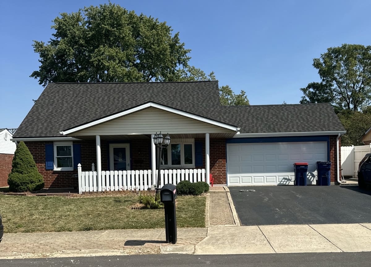 Ranch home behind a white picket fence with a finished dark gray roof
