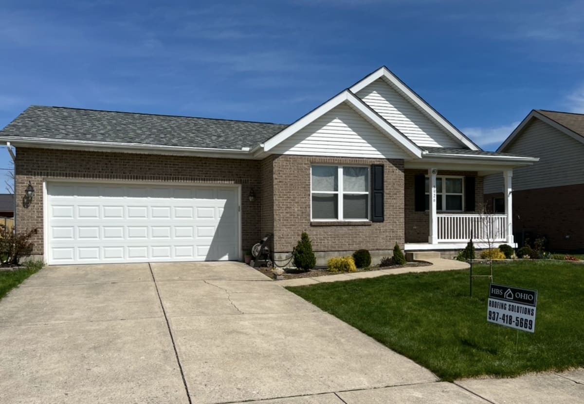 Brick ranch with a two-car garage and a new dark roof, yard sign at the curb