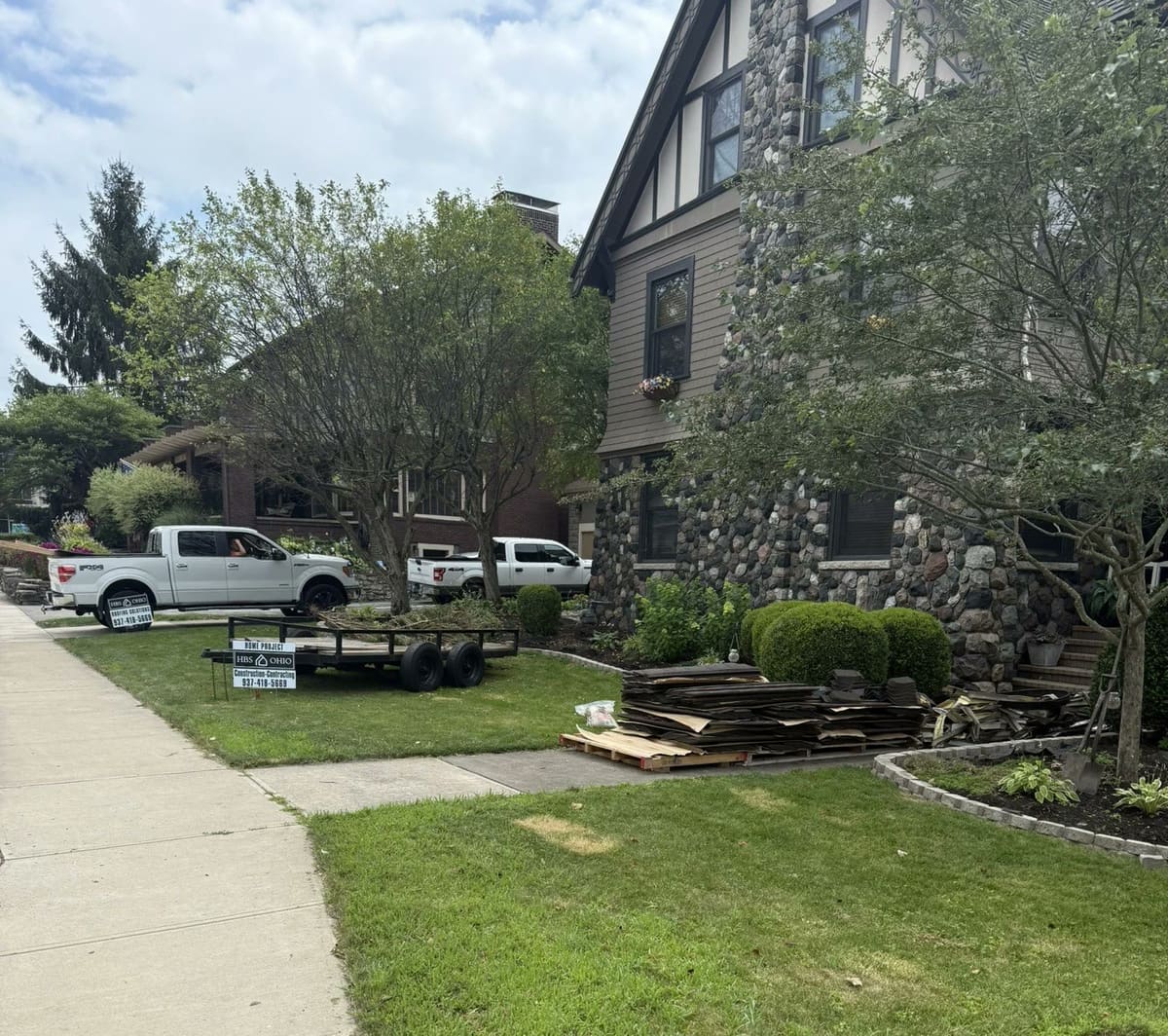 Large two-story home with crew trucks parked in the driveway during a job