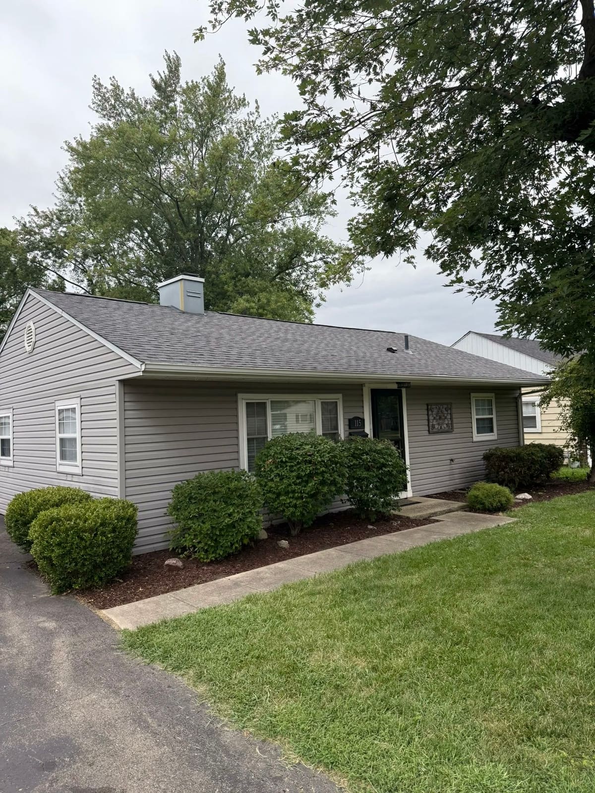 Gray ranch with a completed architectural shingle roof and a brick chimney