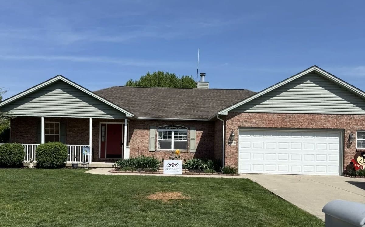 Brick ranch with a red front door and a completed roof, Ohio Roof Pros sign in the yard