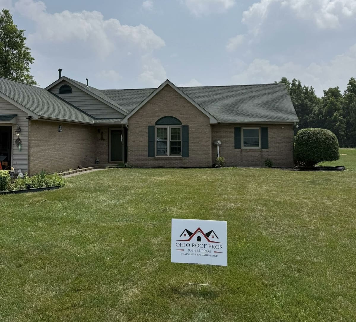 Brick ranch with green shutters, a finished roof and an Ohio Roof Pros sign on the lawn