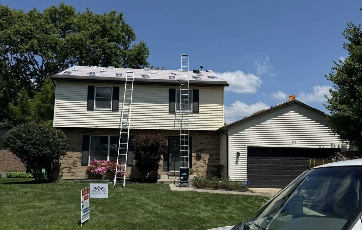 Two-story home dried in during a replacement, ladders standing at the eave