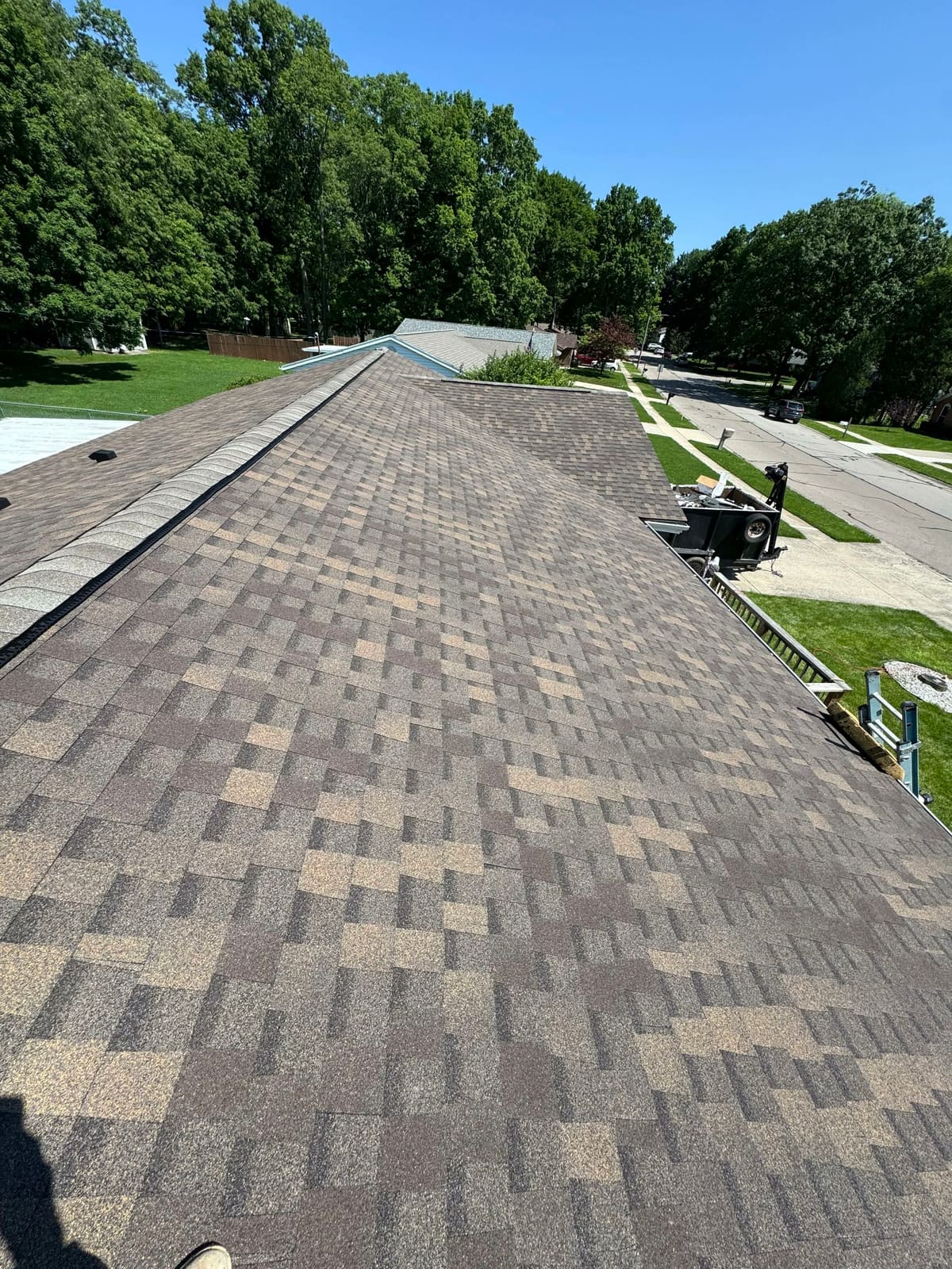 View down the ridge of a finished weathered-wood shingle roof toward the street